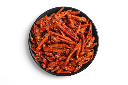 Crispy chili pepper snack with sesame in a black bowl