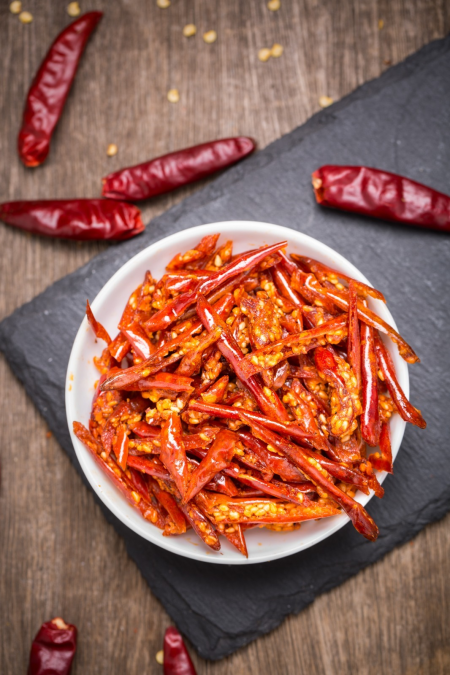 Crispy chili pepper snack with sesame in a white bowl on slate